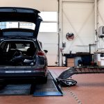 Unfallauto mit offenem Heck und daneben liegenden Autoteilen
